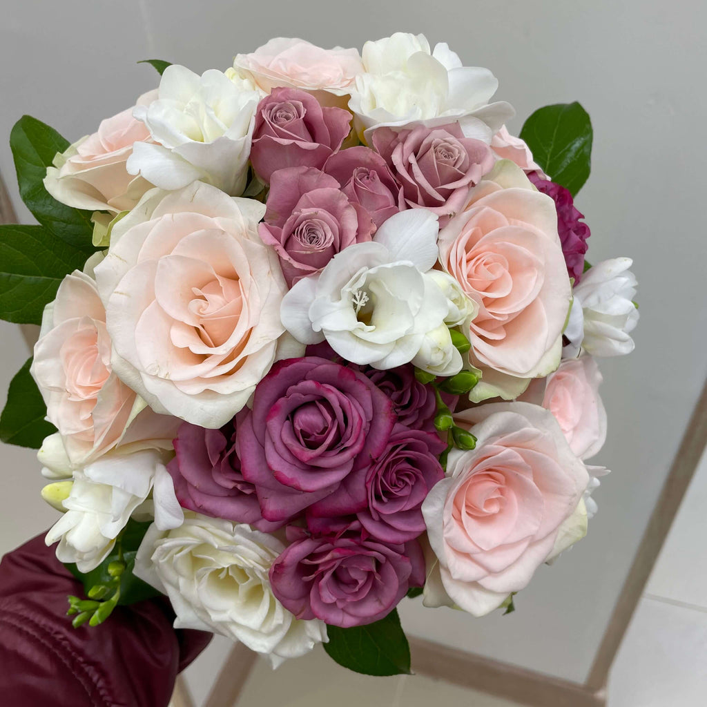 Tall, elegant bouquet of pink orchids and eucalyptus and roses, wrapped in delicate pink paper with a ribbon.