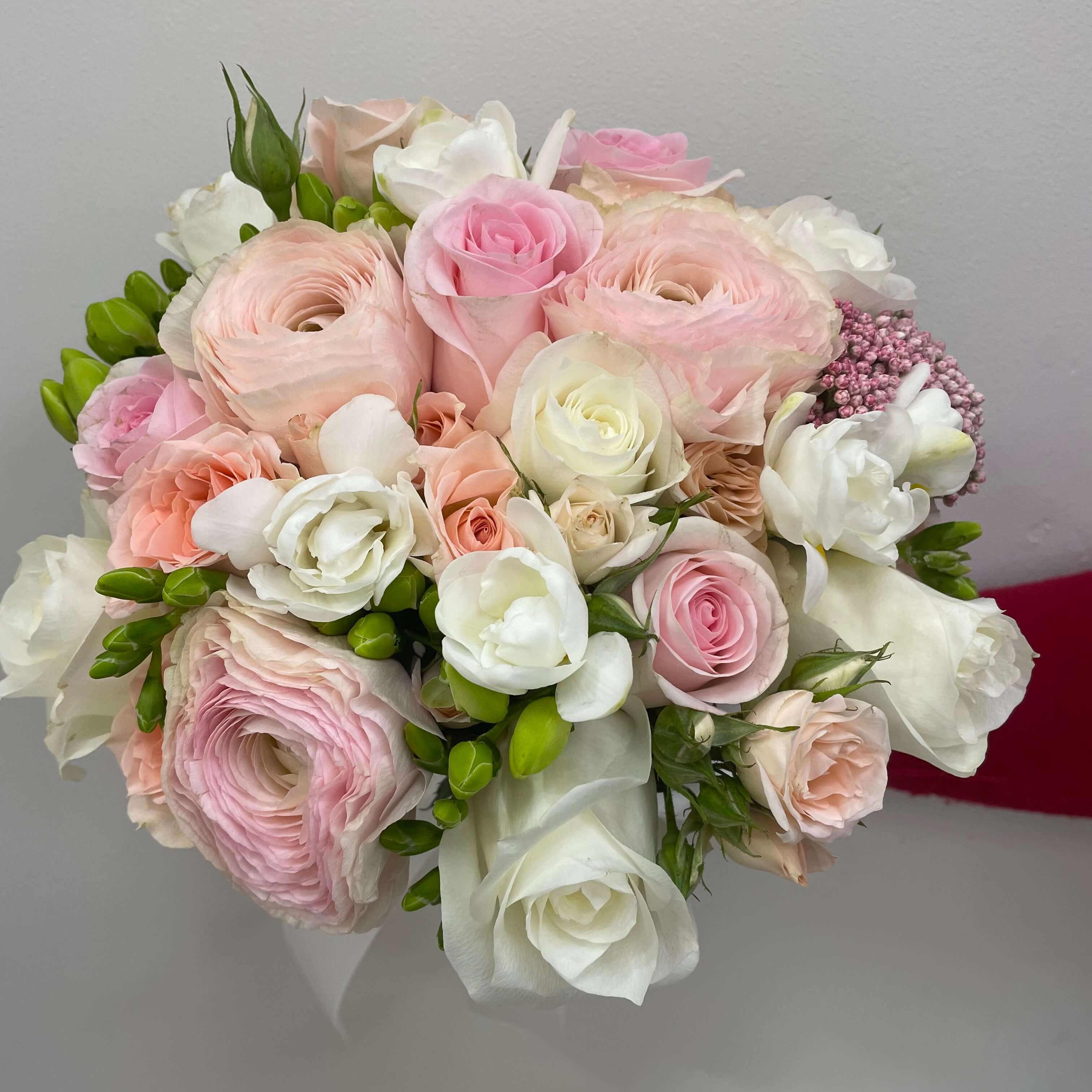 Romantic bouquet of pastel roses, ranunculus, and freesias in soft pink and ivory tones.