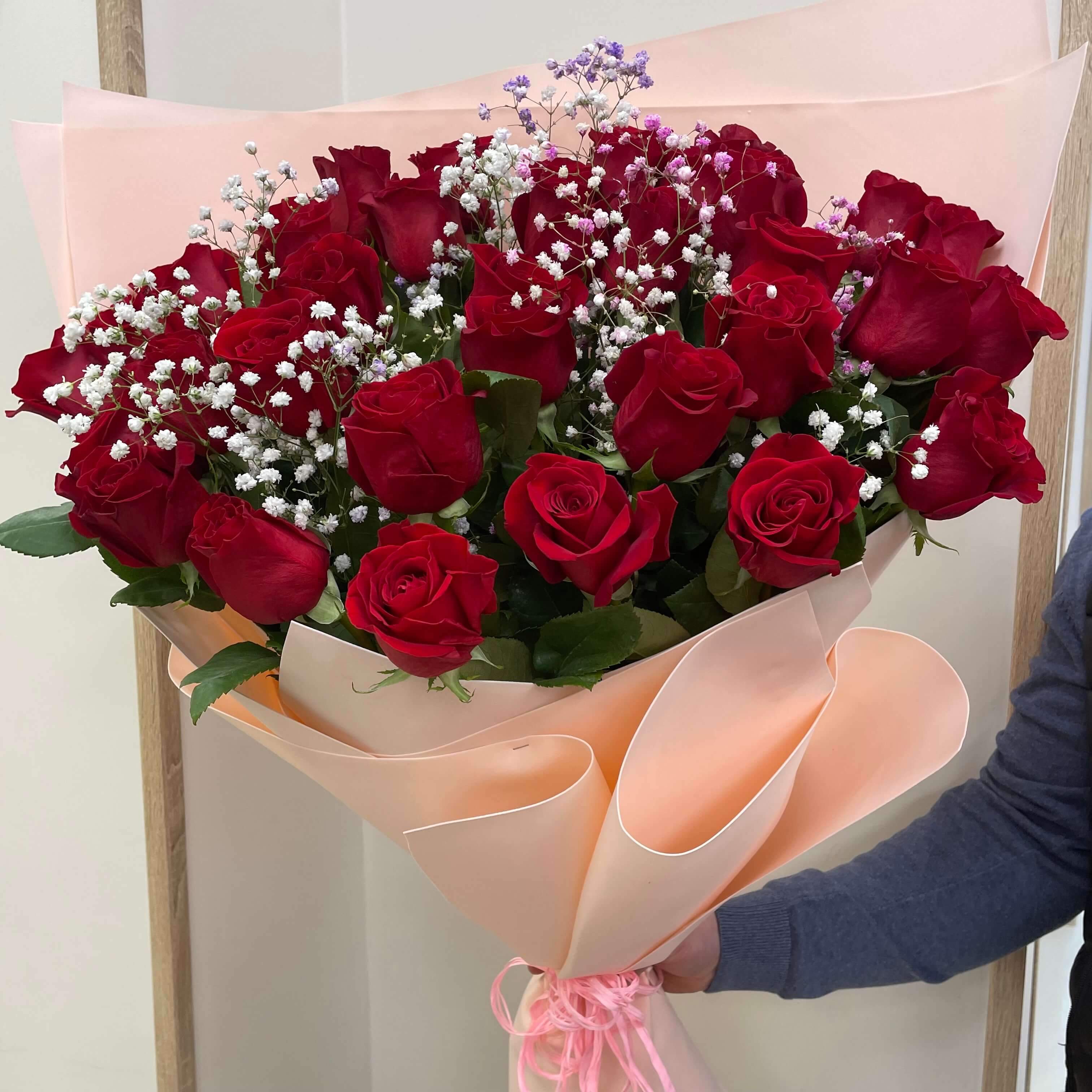 Classic bouquet of red roses accented with delicate baby’s breath, wrapped in soft peach paper.