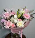 Delicate floral composition with pink and white roses, gerbera daisies, and soft greenery.