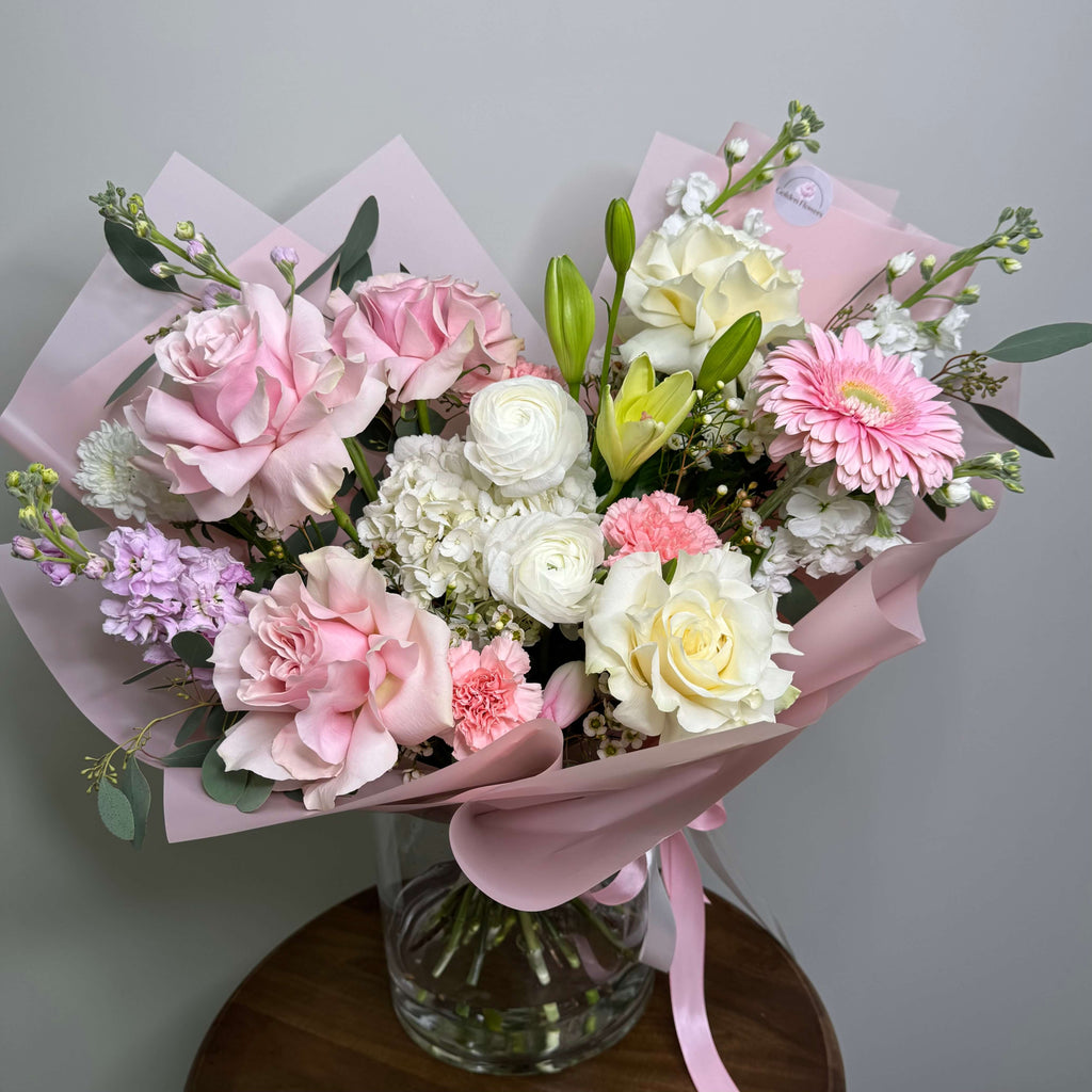 A breathtaking arrangement of peach and ivory roses with eucalyptus and baby's breath, elegantly placed in a white floral box.