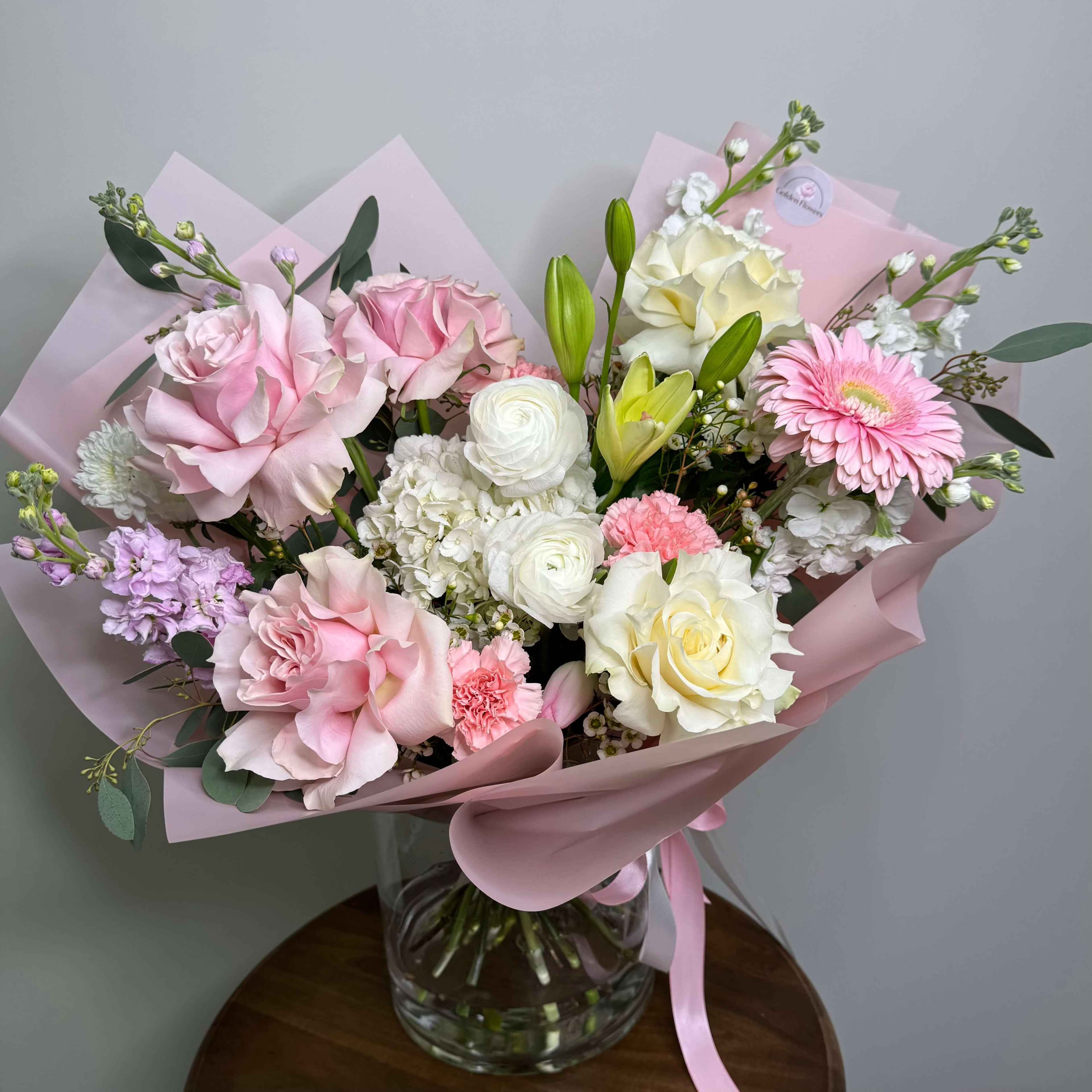 A breathtaking arrangement of peach and ivory roses with eucalyptus and baby's breath, elegantly placed in a white floral box.